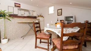 Un coin repas avec une table ronde, des chaises, un téléviseur et une plante en pot.