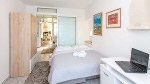 A bedroom with a bed, a desk with a laptop, a wardrobe, and a door leading to a bathroom. - Apartments Tino- Two Bedroom Apartment With Balcony and Sea View (Sutivan)