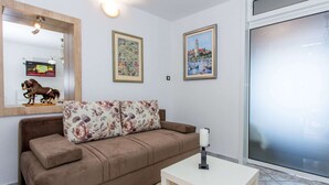 A living room with a brown sofa, two floral cushions, a white side table, and two framed pictures on the wall. - Apartments Tino- Two Bedroom Apartment With Balcony and Sea View (Sutivan)