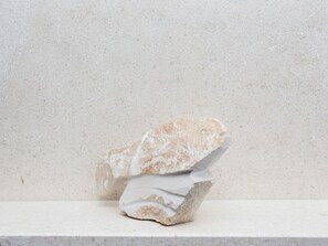 Una escultura de piedra sobre un pedestal frente a un fondo liso.