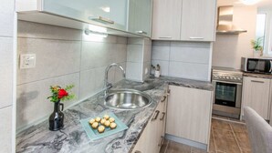 A modern kitchen with a marble countertop, stainless steel sink, and light wood cabinets. - Apartments Tino- Two Bedroom Apartment With Balcony and Sea View (Sutivan)