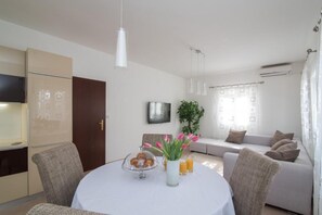 Una sala de estar moderna con una mesa de comedor, un sofá, un televisor y una planta.