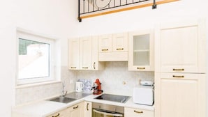 A compact kitchen with white cabinets, a built-in oven, a coffee maker, and a toaster. - Apartments Nikola - Comfort One Bedroom Apartment With City View (Dubrovnik)