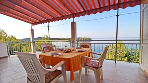 A terrace with a table set for dining, overlooking a body of water.