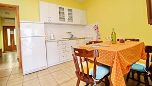 A compact kitchen with white cabinets and a dining area with a polka-dotted tablecloth.