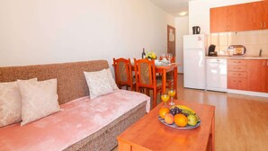 A compact living space with a sofa, dining table, and kitchenette. - Apartments Island Beat - Two Bedroom Apartment With Balcony and Sea View (Supetar)