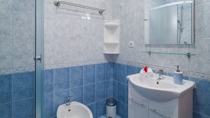 A bathroom with a glass shower enclosure, a white sink with a mirror above it, and a blue-tiled wall. - Apartments Island Beat - Two Bedroom Apartment With Balcony and Sea View (Supetar)