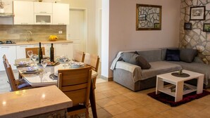 A modern living room with a dining area, a grey sofa, and a small white side table. - Holiday Home Luna - Two Bedroom Holiday Home With Sea View (Korcula)