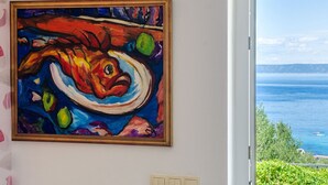A painting of a fish on a wall, a window with a view of the sea, and a door. - Vacation House Marija, Korcula-two Bedroom Holiday Home With Terrace and Sea View (Korcula)