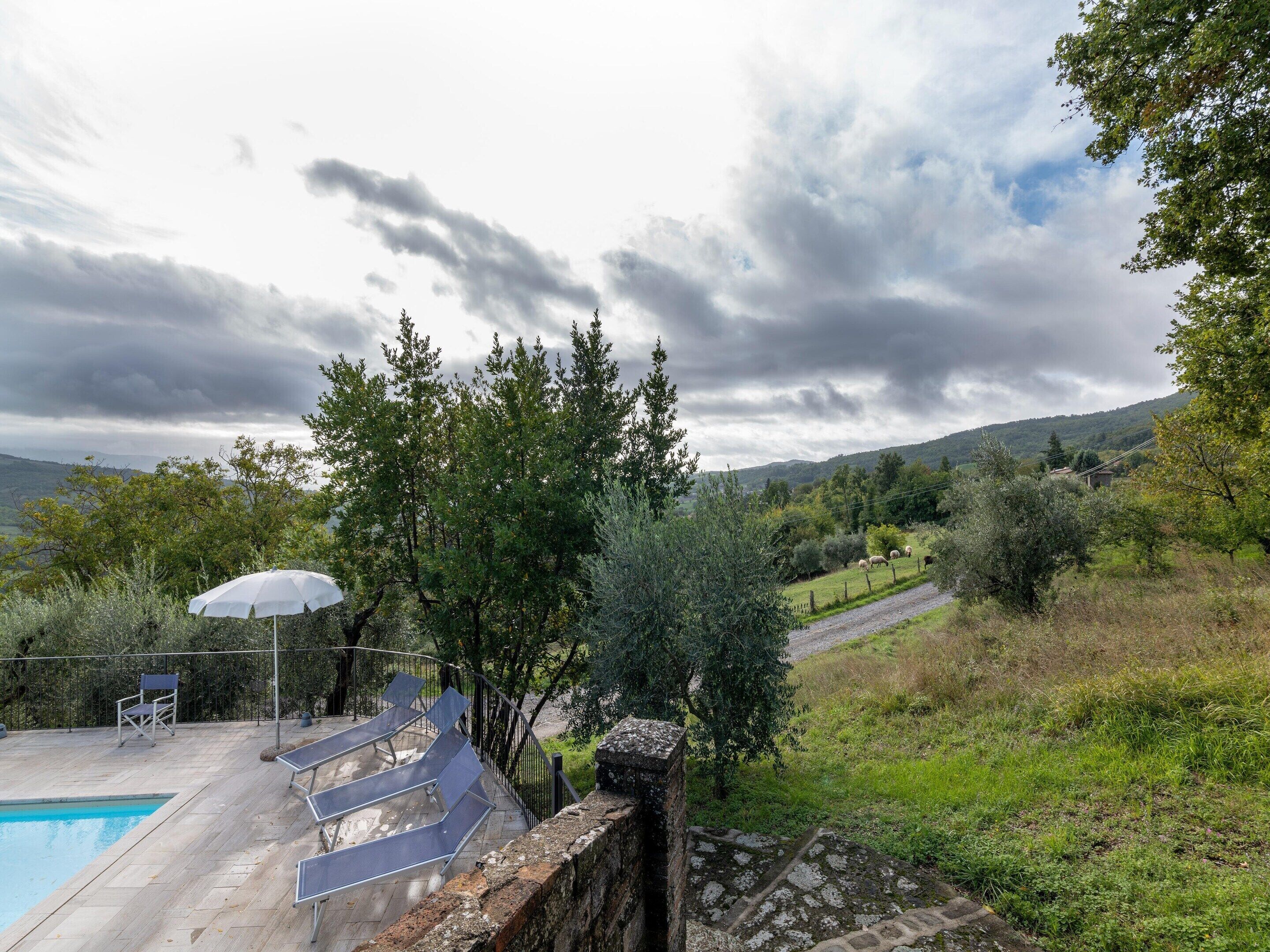 A pool area with a view of the countryside, including trees and hills.