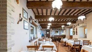 A restaurant with wooden beams and white tables set for dining. - Belvilla by OYO Casa Granaio (Caprese Michelangelo)