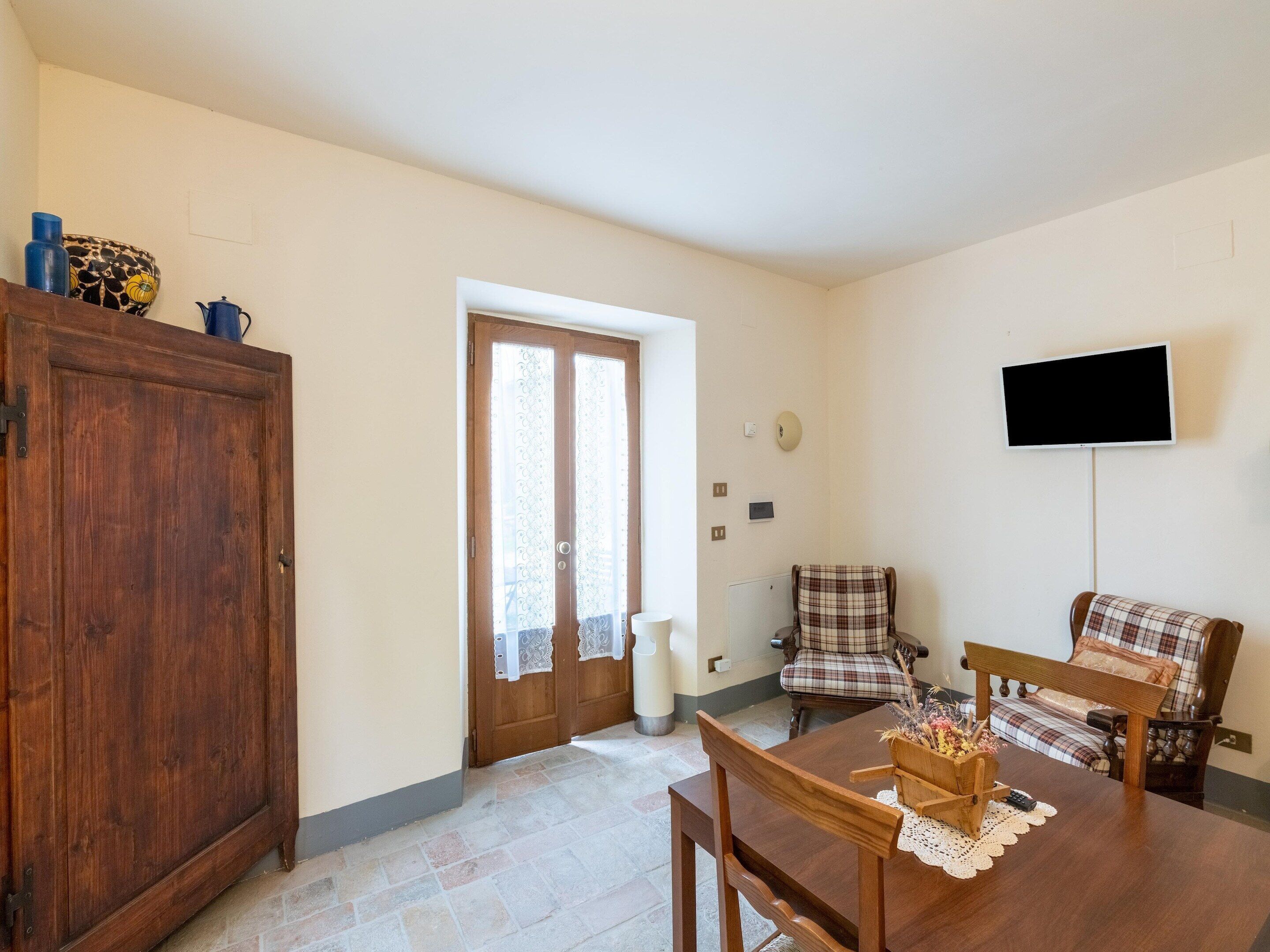A dining area with a wooden table, chairs, and a television mounted on the wall.
