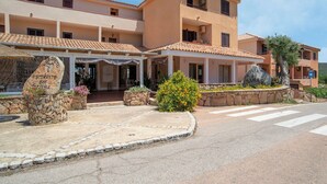 A two-story building with a covered entrance, stone pillars, and a sign indicating a restaurant and bar. - Belvilla by OYO Monolocale Baia 8 (Golfo Aranci)