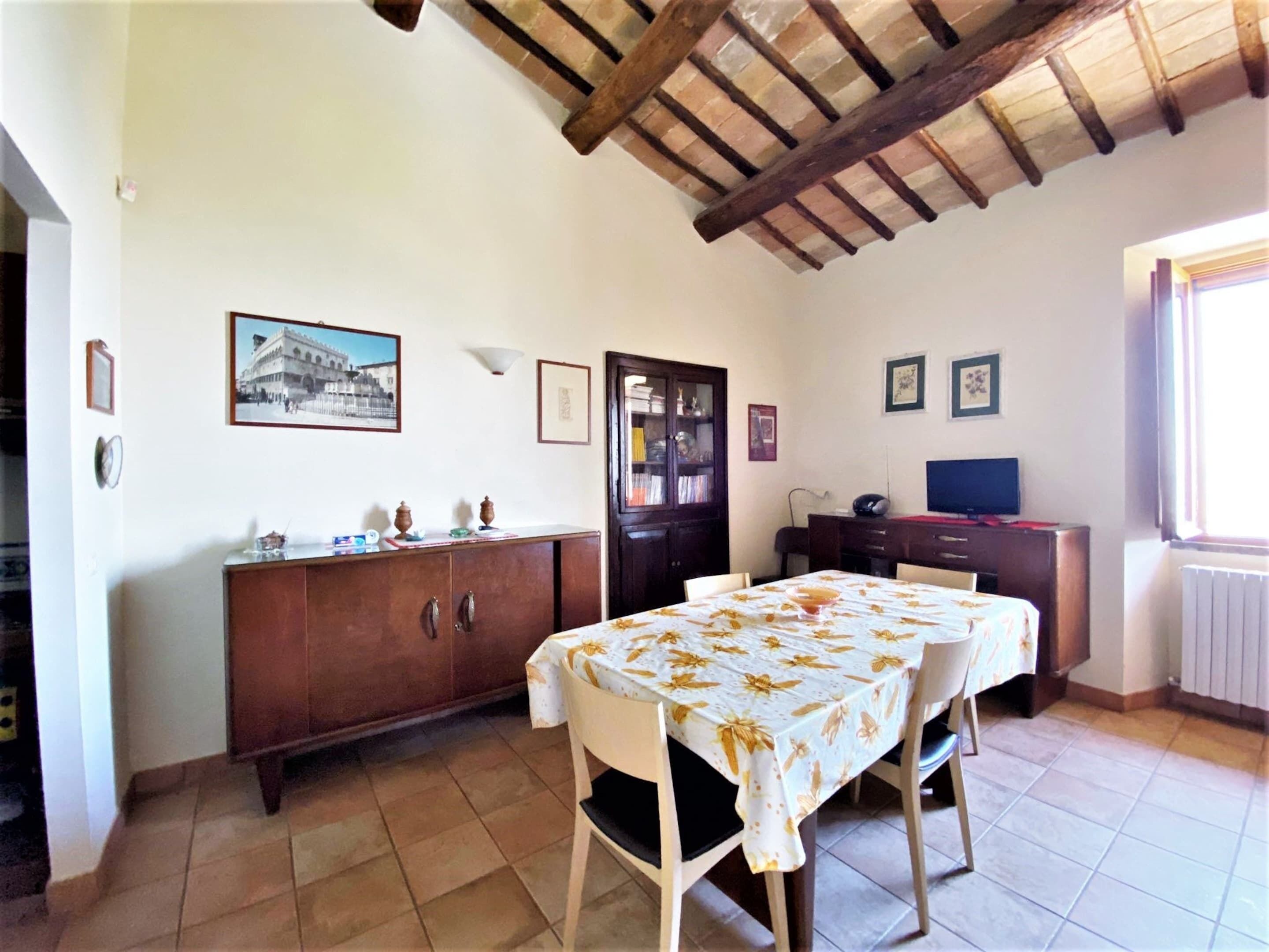 Un comedor con una mesa y sillas de madera, un armario y un televisor.