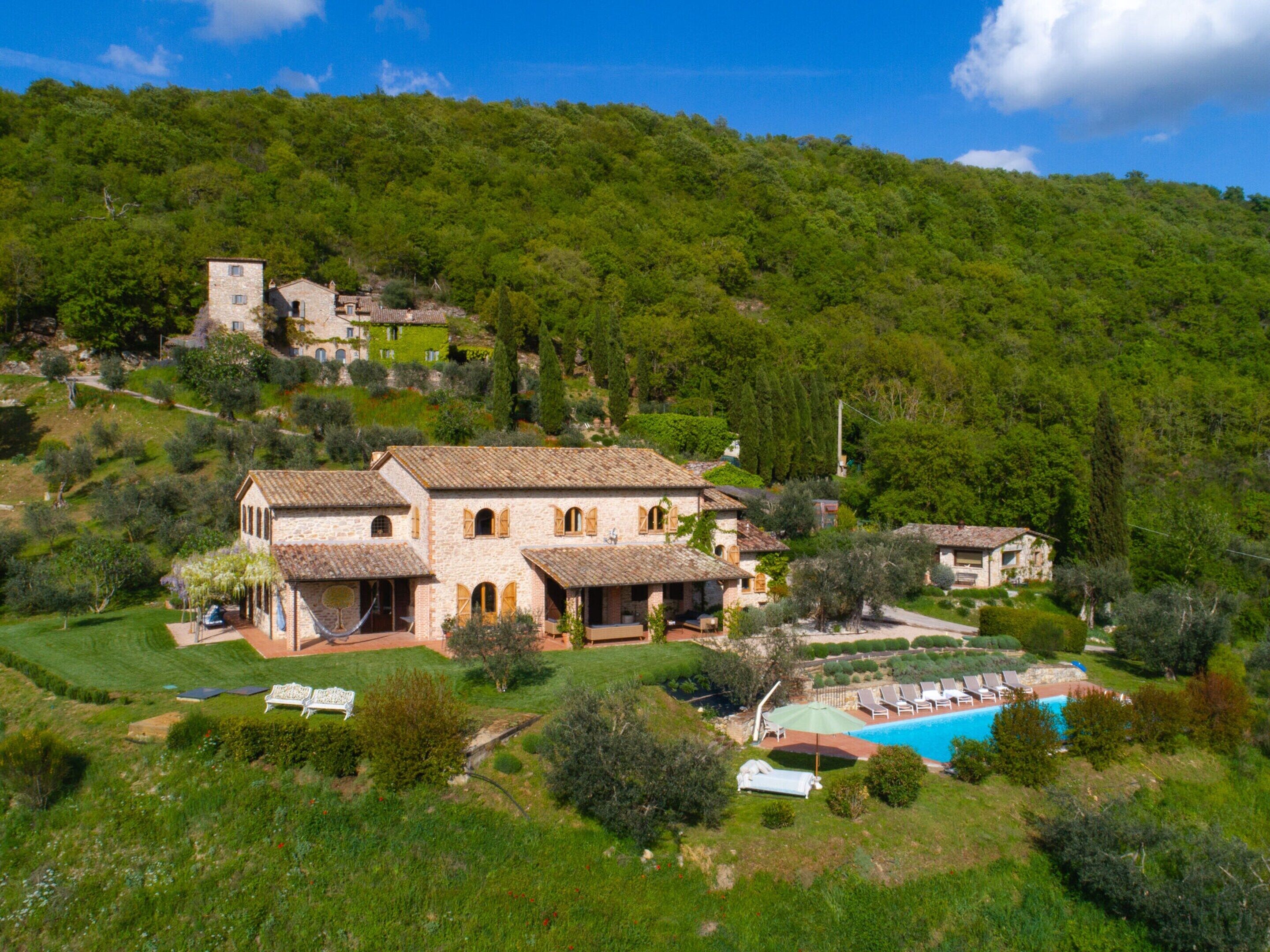 A hillside villa with a swimming pool, surrounded by lush greenery and traditional architecture.