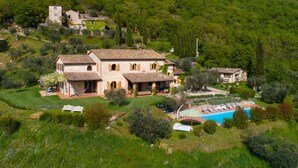 Une villa située sur une colline, dotée d’une piscine et entourée d’une végétation luxuriante, dans un style architectural traditionnel.