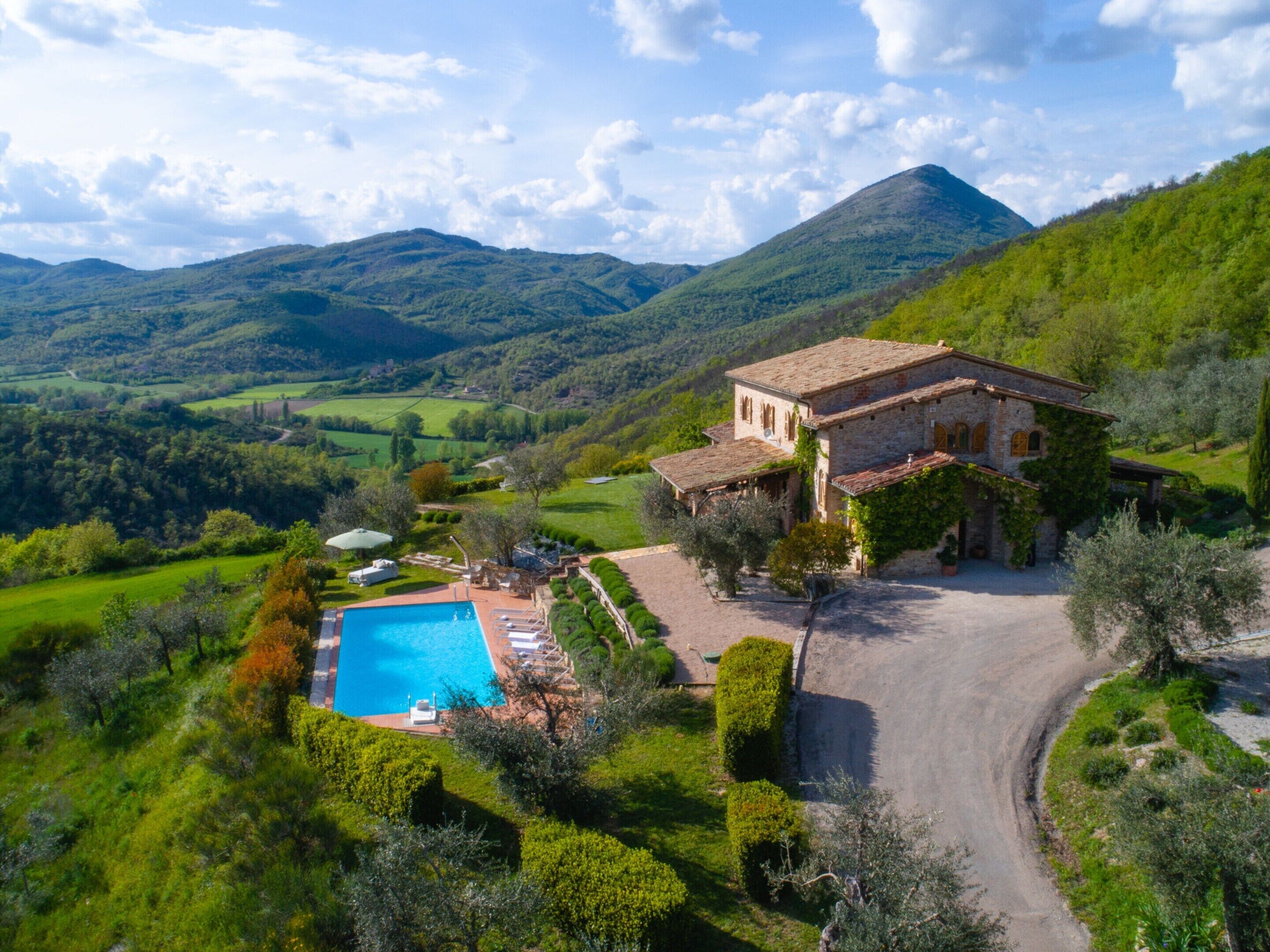 Una villa con piscina, rodeada de exuberante vegetación y montañas.