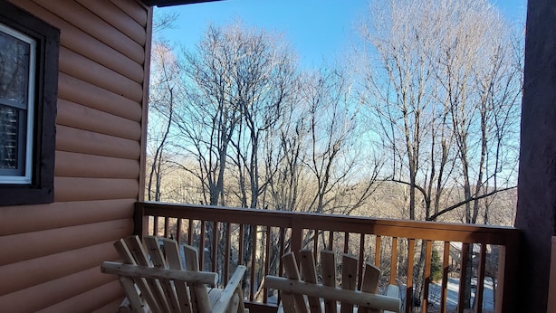 A wooden deck with two Adirondack chairs facing a view of leafless trees and a clear sky. - Cozy ski  retreat, close to Appalachian ski mountain in blowing rock and boone  (Blowing Rock)