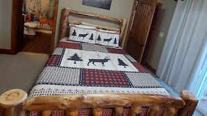 A bedroom with a wooden bed frame, a ceiling fan, a painting of a forest scene, and a window with curtains. - Cozy ski  retreat, close to Appalachian ski mountain in blowing rock and boone  (Blowing Rock)