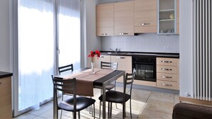 A modern kitchen with light wood cabinets, a black countertop, and a built-in oven. - Apartment by Lake Como With Scenic Views (Dervio)