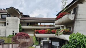 A multi-story building with balconies adorned with flowers, a gated entrance, and a cobblestone pathway. - Pleasant Apartment by the Lake (Baveno)