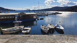 A marina with several boats docked, a pier with a boat named "Da Goc," and a mountainous backdrop. - Pleasant Apartment by the Lake (Baveno)