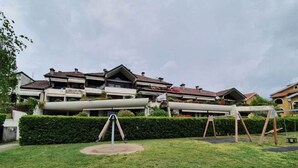 A residential area with a grassy lawn, a swing set, and a large pipe structure. - Pleasant Apartment by the Lake (Baveno)