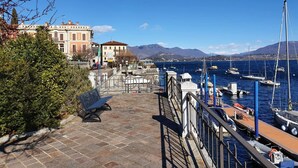 A marina with boats docked, a stone pathway, and buildings with balconies. - Pleasant Apartment by the Lake (Baveno)