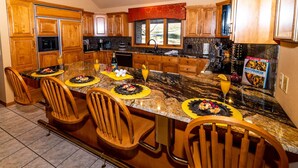 A spacious kitchen with wooden cabinets, a granite countertop, and a dining area with four wooden chairs. - Gorgeous View, HotTub, Great Games, Stories Around the Fire! (Guilford Township)