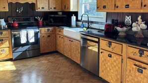 A kitchen with wooden cabinets, a stainless steel stove, and a wooden herringbone floor. - The Owl Barn - Most Unique Cabin in The Smokies. Hot Tub, Family & Pet Friendly (Sevierville)