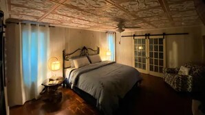 A bedroom with a large bed, ornate ceiling, and a sliding glass door to the right. - The Owl Barn - Most Unique Cabin in The Smokies. Hot Tub, Family & Pet Friendly (Sevierville)