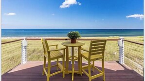 Une terrasse avec une table et des chaises donnant sur une plage.