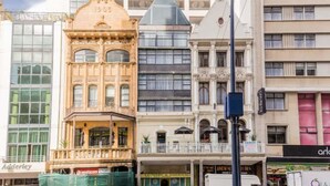 A multi-story building with a prominent corner entrance, a sign reading "1500", and a visible storefront with a sign that appears to say "arld". - 1 Bedroom Apartment With Roof Top Views (Cape Town)