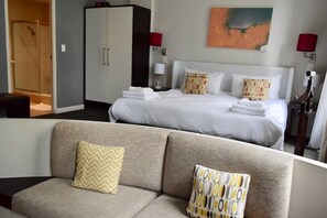 Een hotelkamer met een bed, een slaapbank, een garderobe en een douche.