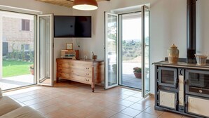 A spacious living area with a fireplace, a television mounted on the wall, and a wooden cabinet with drawers. - Belvilla by OYO Villa Intera 12 Pax (Collecorvino)