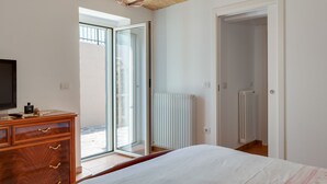 A bedroom with a bed, dresser, and a view through a glass door to an outdoor area. - Belvilla by OYO Villa Intera 12 Pax (Collecorvino)