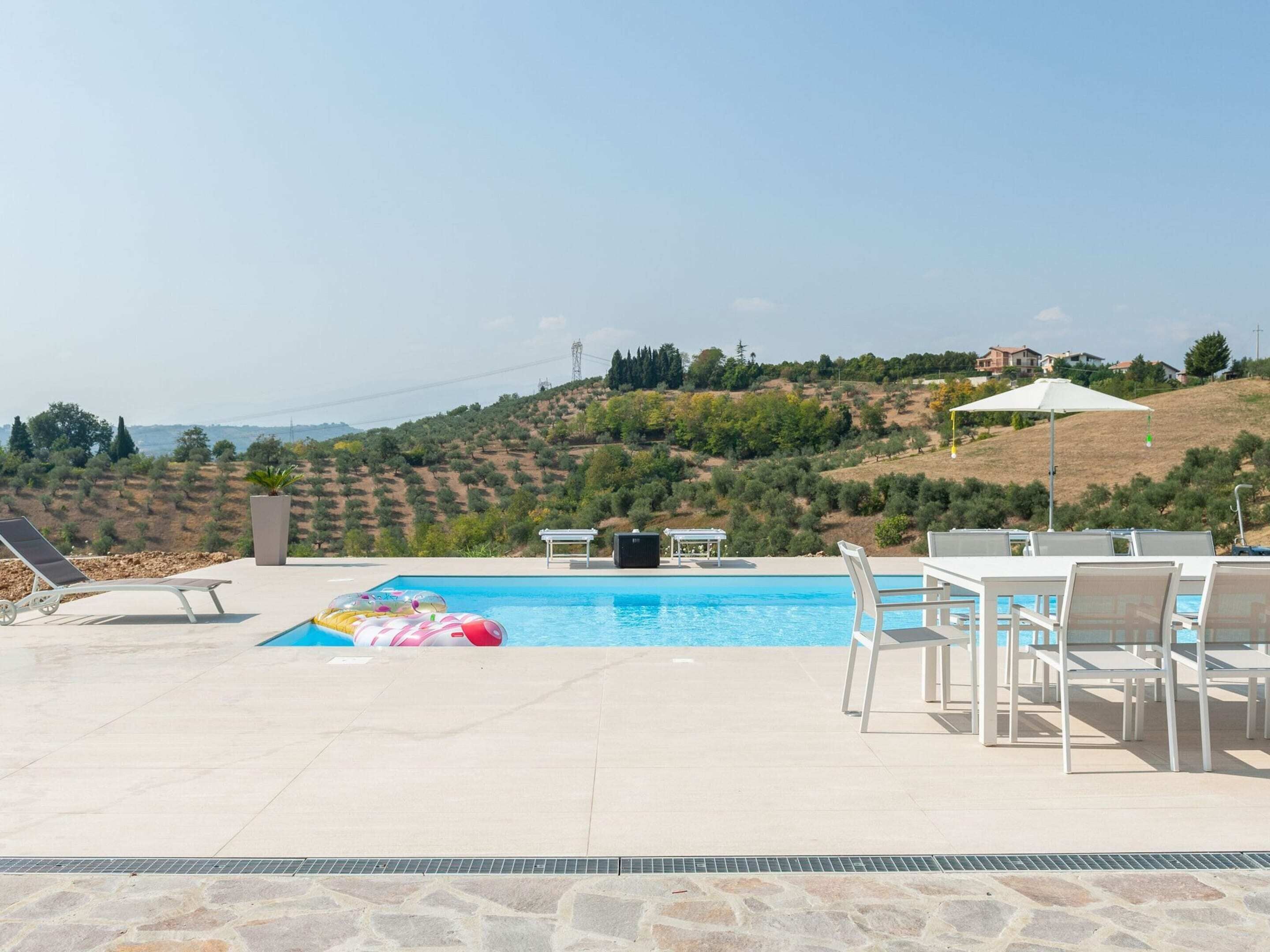 Ein Pool mit Liegestühlen und einem Tisch, umgeben von einer Steinterrasse.