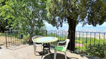 Un'area salotto all'aperto con tavolo e sedie, circondata da un recinto in metallo e alberi.
