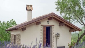 A small stone building with a tiled roof, a chimney, and a door. - Belvilla by OYO Bilocale 2adeg Piano (Assisi)