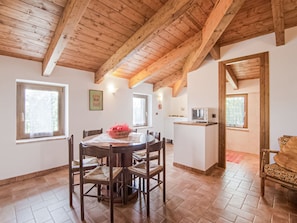 Un coin repas avec un plafond en bois, une table ronde et des chaises. Il y a également un coin cuisine équipé d’un four à micro-ondes et d’une fenêtre.