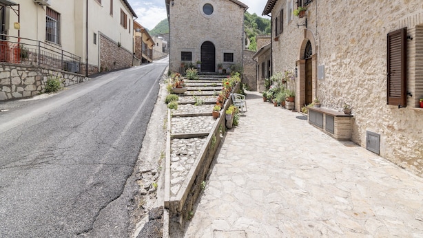 A narrow street leading to a stone building with a bell tower, surrounded by stone walls and potted plants. - Belvilla by OYO Casa Polino (Polino)