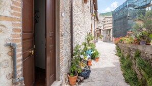 A narrow alleyway with a stone building, wooden doors, and potted plants lining the path. - Belvilla by OYO Casa Polino (Polino)