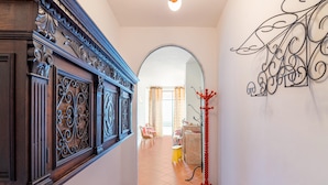 A hallway with a wooden door, a metal coat rack, and a decorative wall piece. - Belvilla by OYO Casa Polino (Polino)