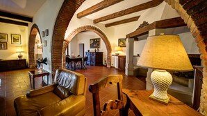 A spacious living area with a leather sofa, wooden table, and a lamp. - Villa by Lake Trasimeno With Scenic Views (Castiglione del Lago)
