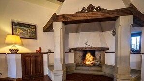 A fireplace with a fire, a wooden mantel, and a painting on the wall. - Villa by Lake Trasimeno With Scenic Views (Castiglione del Lago)