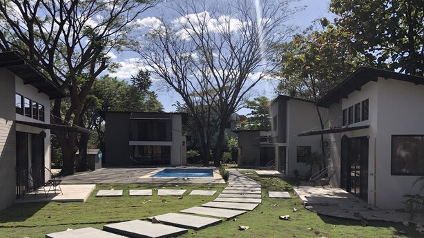 A modern residential area with a swimming pool, paved walkways, and multiple houses. - Honeymoon apt with mini fridge and pool view (Playa junquillal)