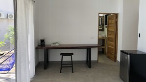 A small, modern kitchen with a wooden table and a stool, a refrigerator, and a view of a balcony with a hammock. - Honeymoon apt with mini fridge and pool view (Playa junquillal)