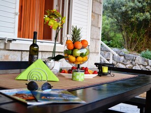 A table with a bottle of wine, a fruit bowl, a green napkin, and a candle.