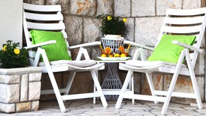 A stone wall with two white chairs and a table, each with a green cushion. - Apartments Lina - Two Bedroom Apartment With Terrace (Dubrovnik)