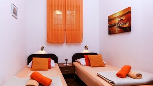 A hotel room with two beds, orange curtains, a painting on the wall, and a small table between the beds. - Apartments Lina - Two Bedroom Apartment With Terrace (Dubrovnik)